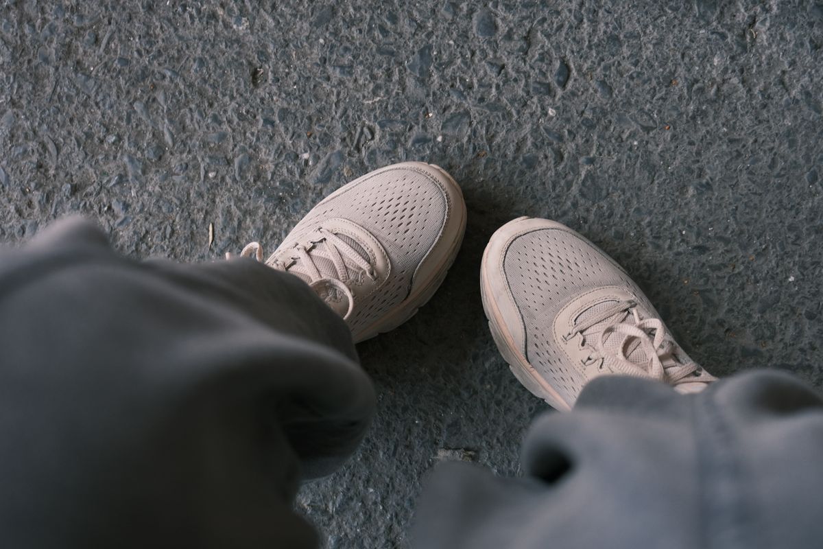 White sneakers walking on textured city pavement
