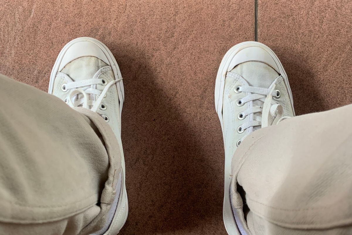 Walking shoes mid-stride on city pavement