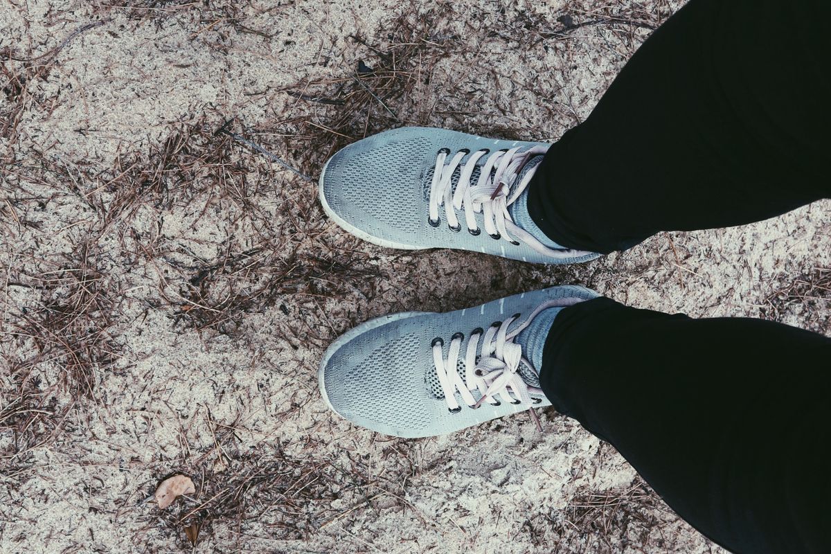 Person in blue sneakers standing on pavement